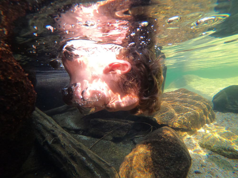 Trevor fully submerging his head underwater as bubbles shoot from his nose.