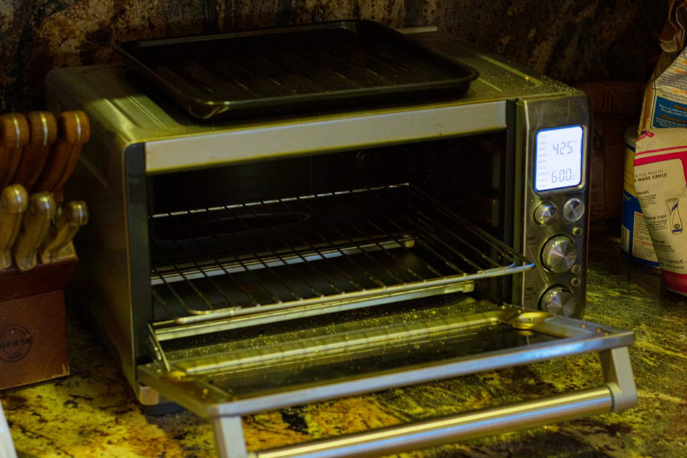 An open toaster oven with a magnet rack extending from its center.
