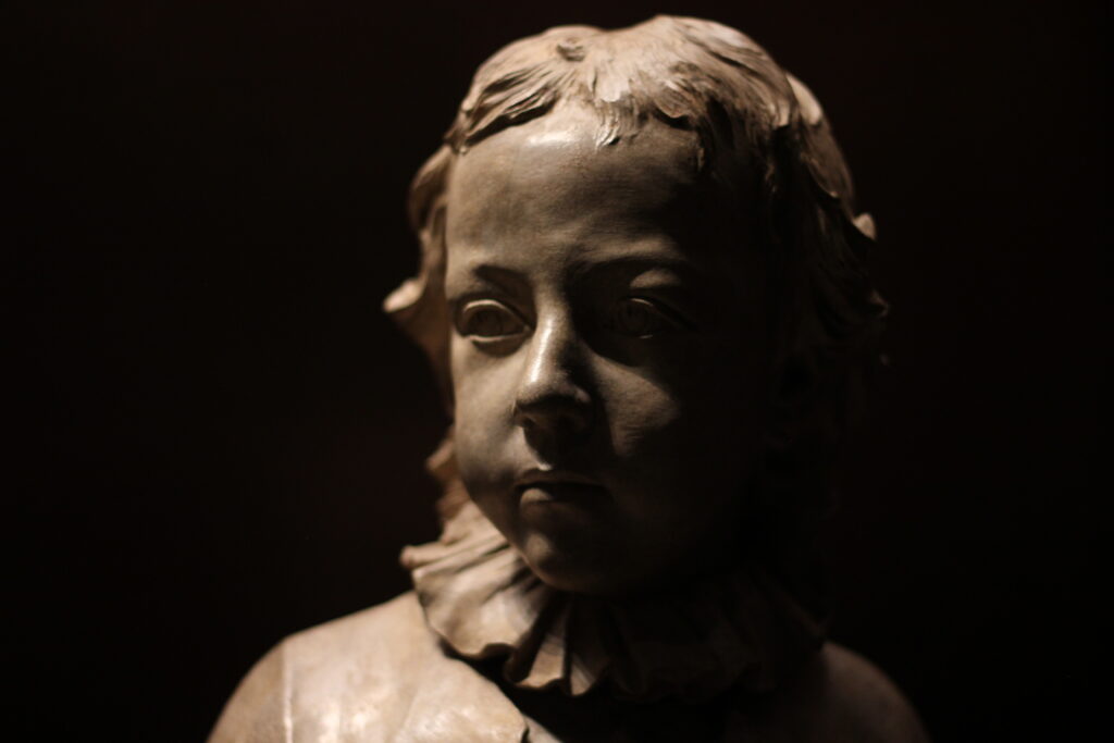 The bust of a child shrouded in shadow