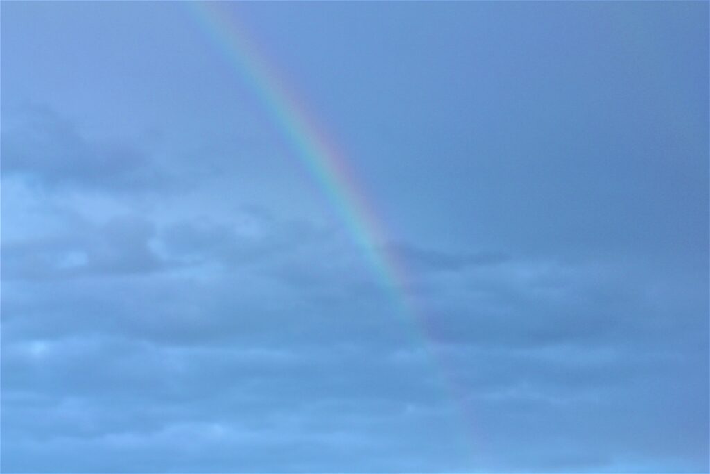 A rainbow in a cloudy blue sky