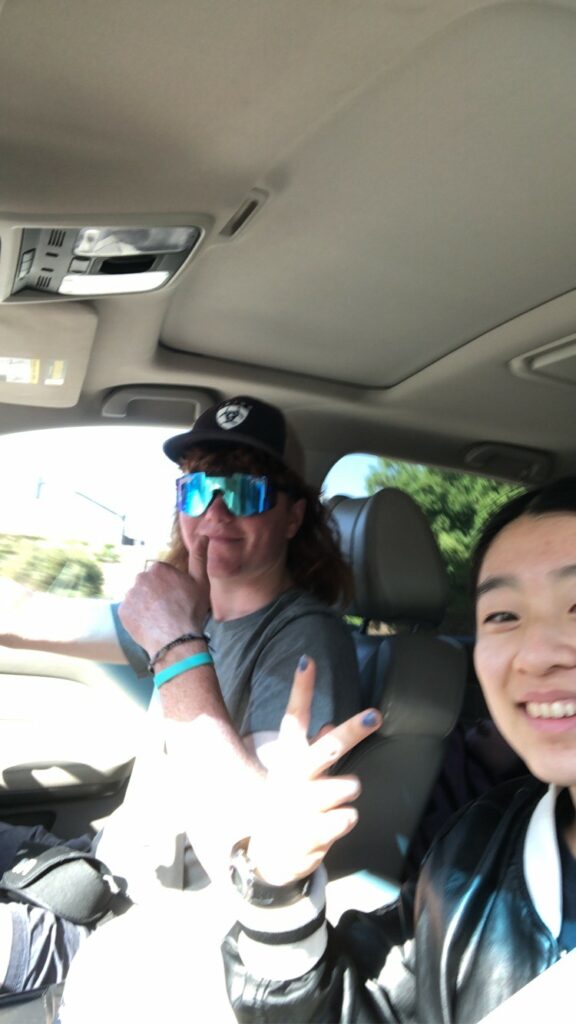 Fiona(me) holding up a peace sign, while Jack flashes a thumbs up with one hand on the steering wheel. He is wearing pit viper sunglasses.