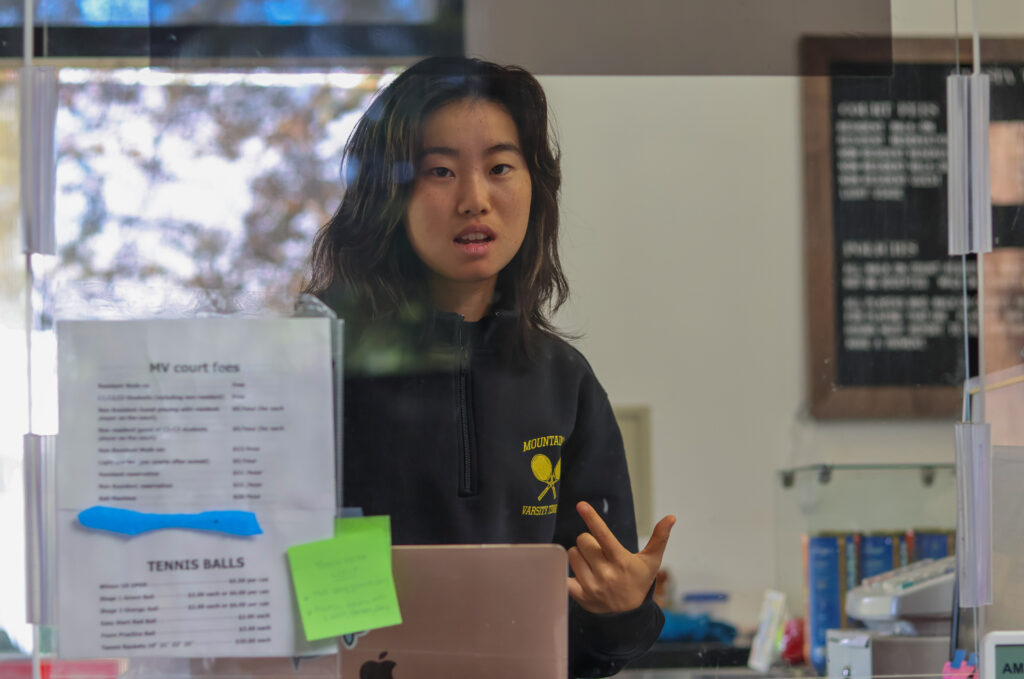 Audrey Shen standing at her desk at her job
