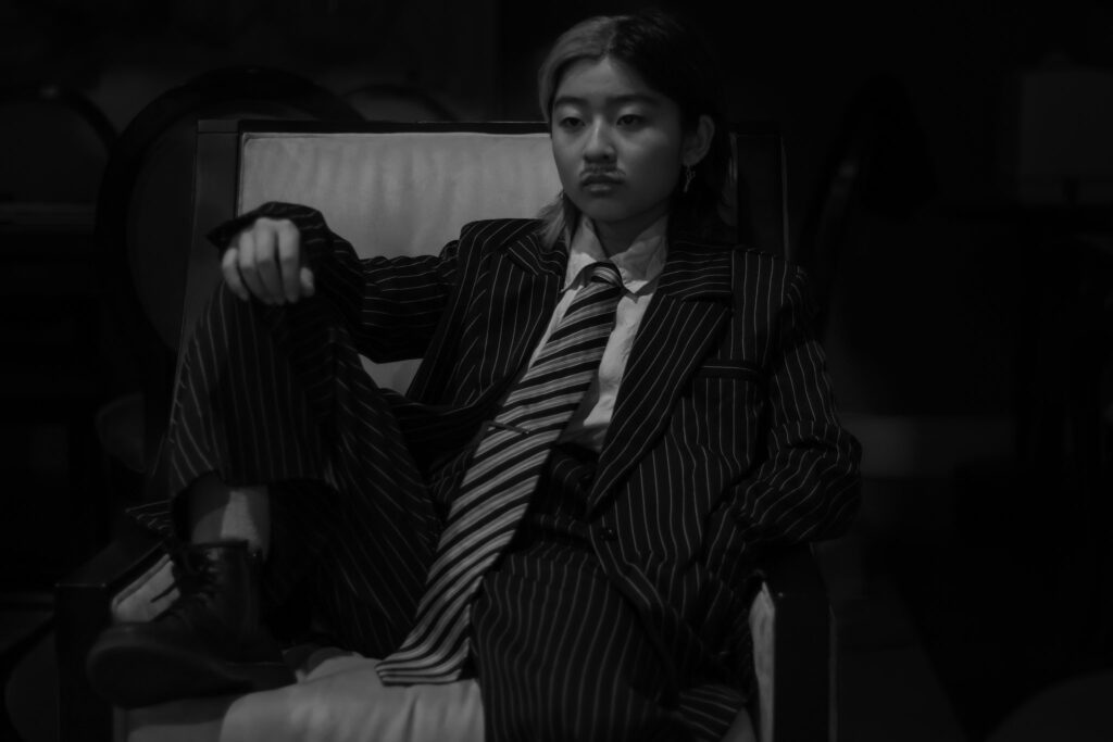 black and white photo of Fin sitting on a chair wearing a suit