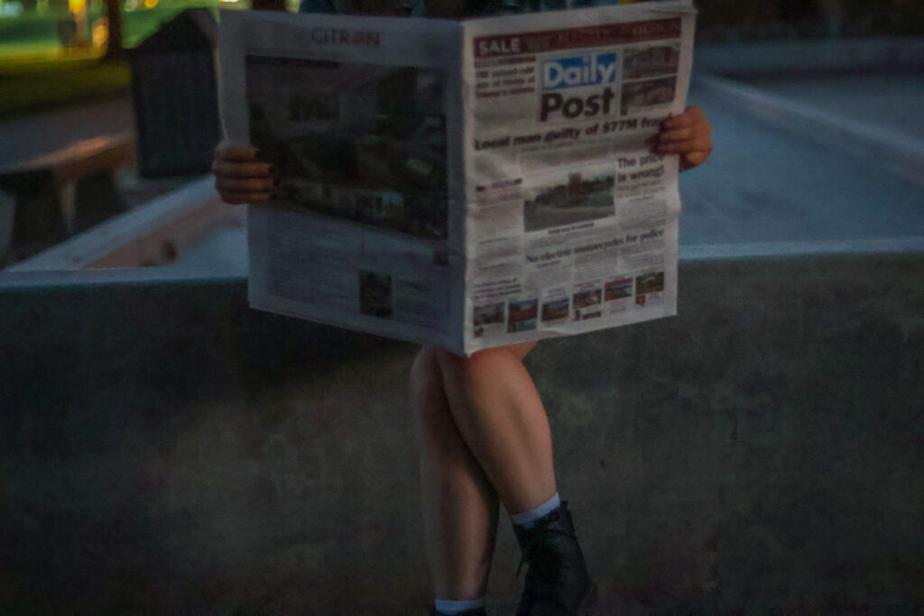 Fin sitting holding an open newspaper