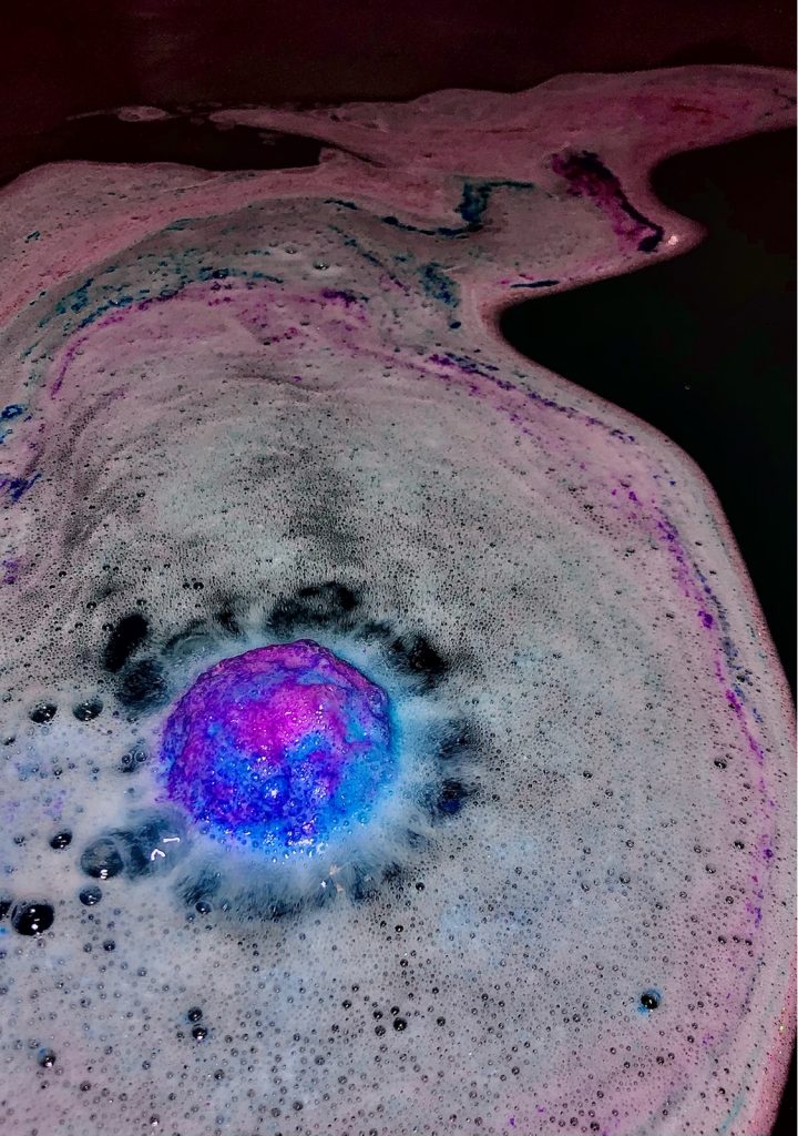 image of a bath bomb fizzing out creating a trail of blue and purple and pink 