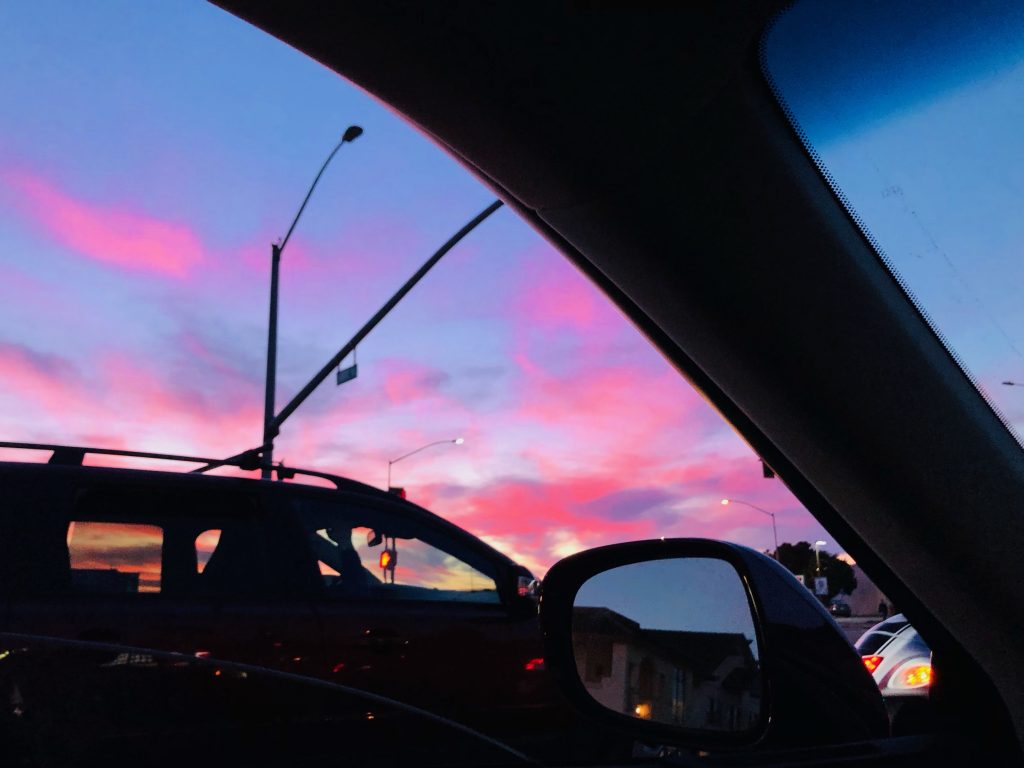 This image captures the view of a car at a stop light with a beautiful sunset in the background