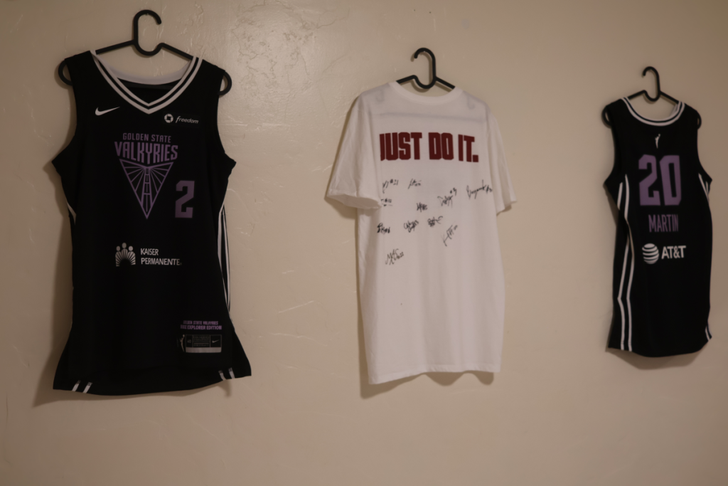 Three basketball jerseys of different styles hang on a plain cream wall.