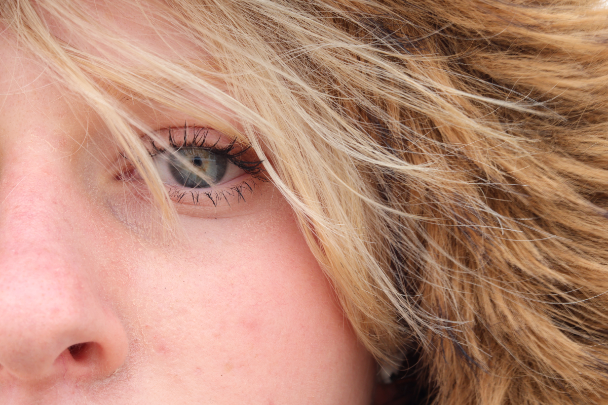 A girls right eye peers into the camera. The reflection of the beach is visible.