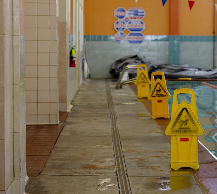 Pool deck with 3 yellow signs on the side of it