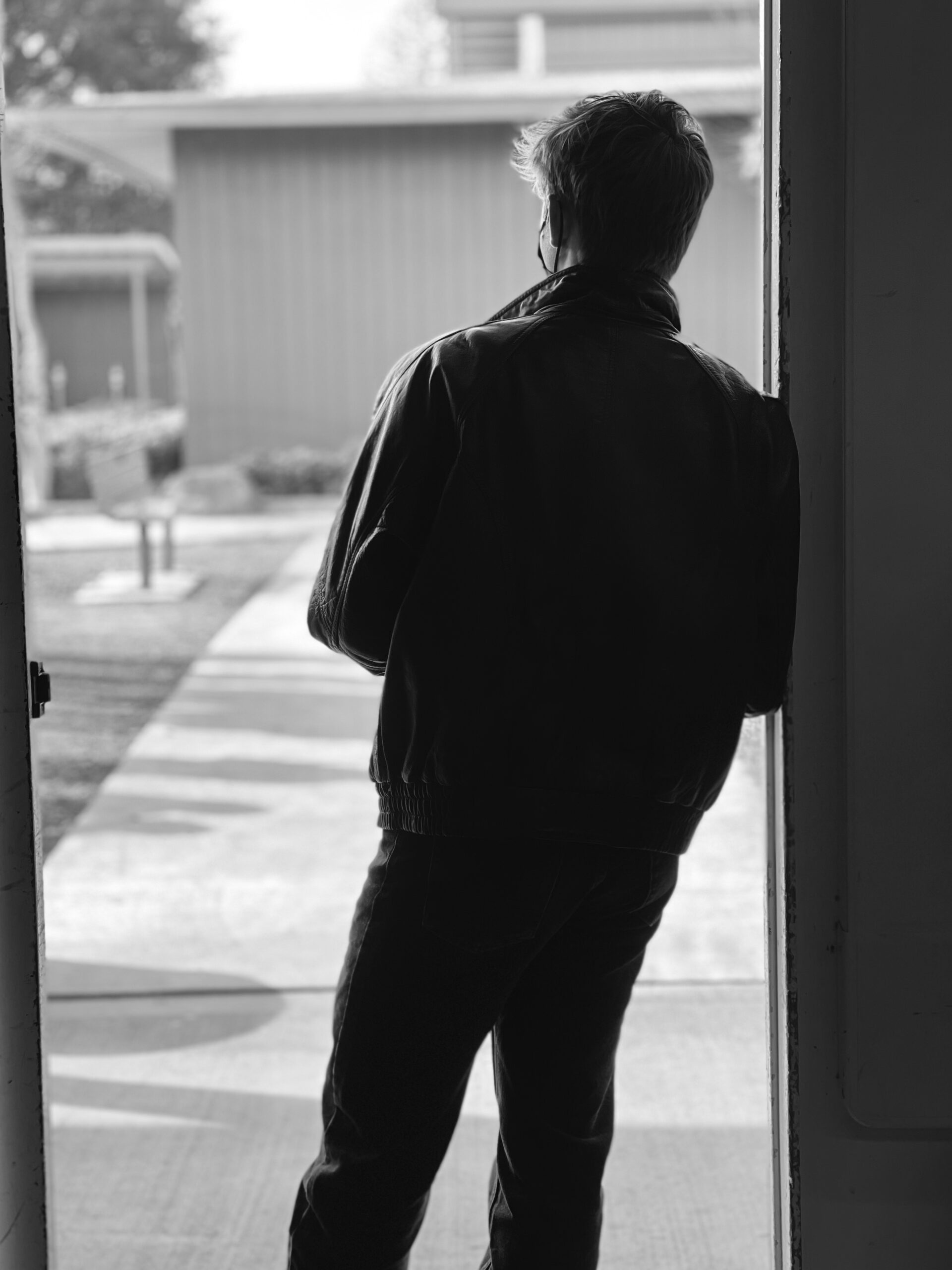 A greaser looking out the window a doorway. 