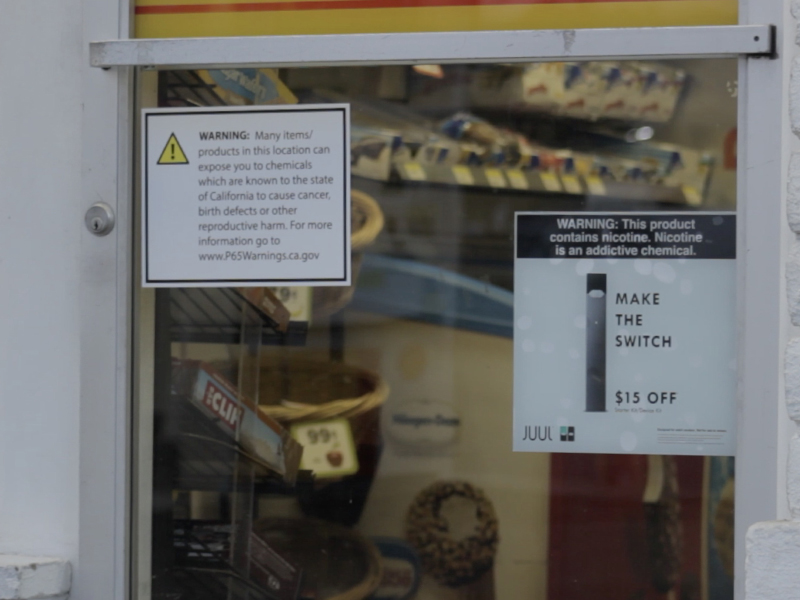 Outside a gas station, there is an advertisement promoting Juul as the 