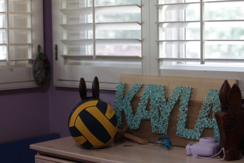 Dresser with wooden name Kayla and waterpolo ball, and mini film camera.
