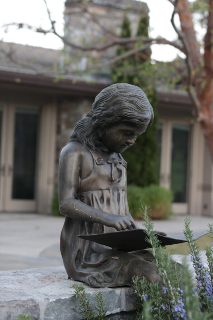 Image of a bronze statue of a girl reading