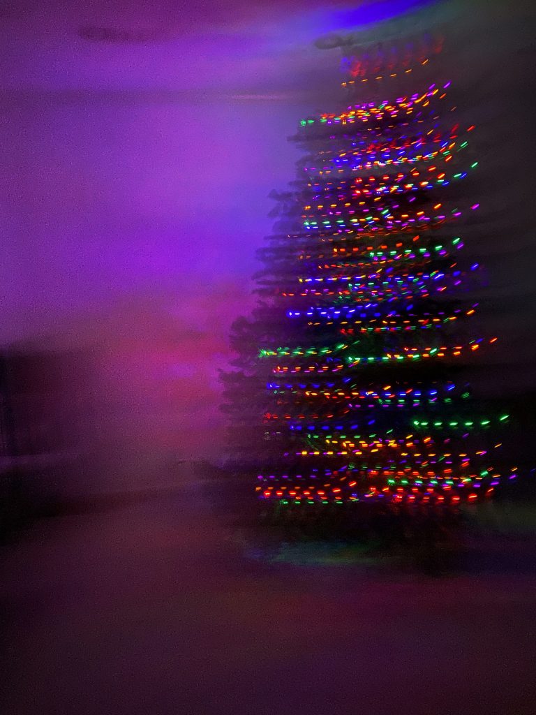 A large christmas tree is in the right corner. The shot is somewhat blurry and dark so it looks like a whirlwind of color. 