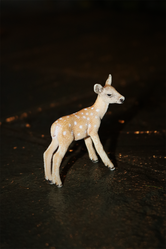 A photograph of a fawn toy standing in the dark for the photo blog prompt "Center Frame: Loneliness".