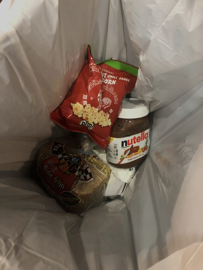 Picture of a trash bag with popcorn, nutella, and loaf of bread
