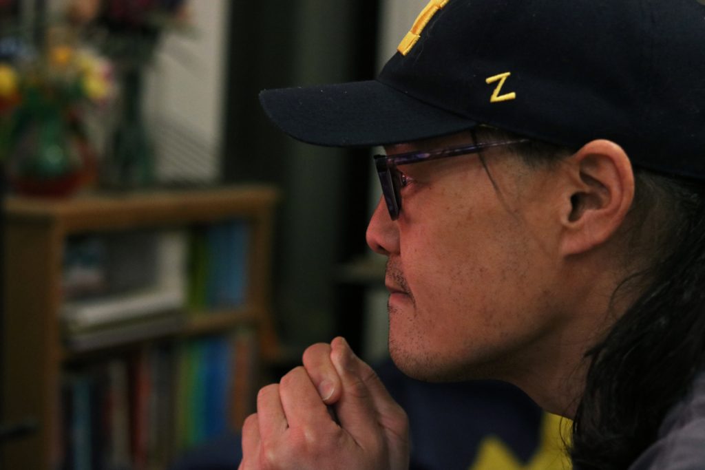 Side profile of man looking at an implied screen outside the frame, man has intense, focused stare.