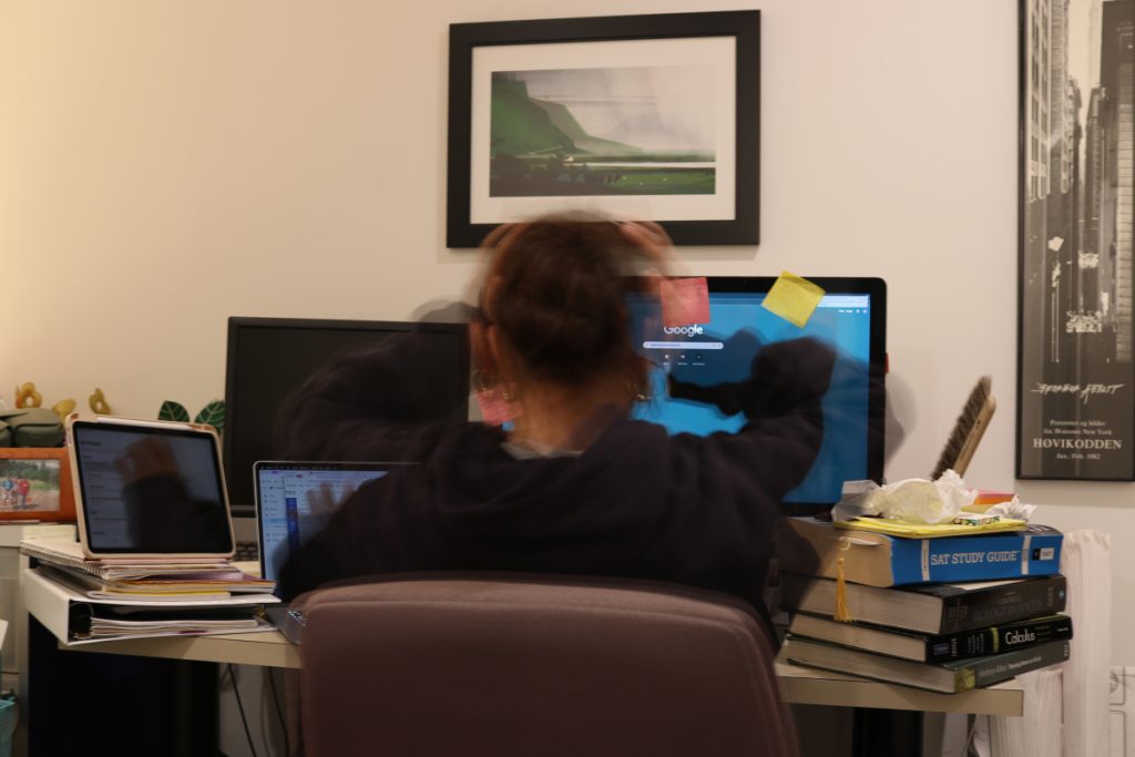 Mira sitting at a desk, back facing to camera with hands on her head and extending out doing multiple activities.