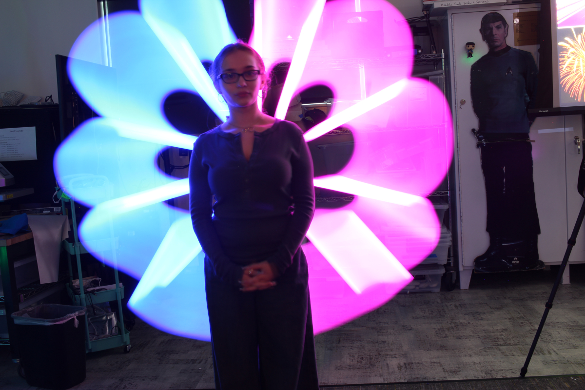 Long exposure picture of girl, Kayla, with half blue and pink flower behind her, drawn with light.