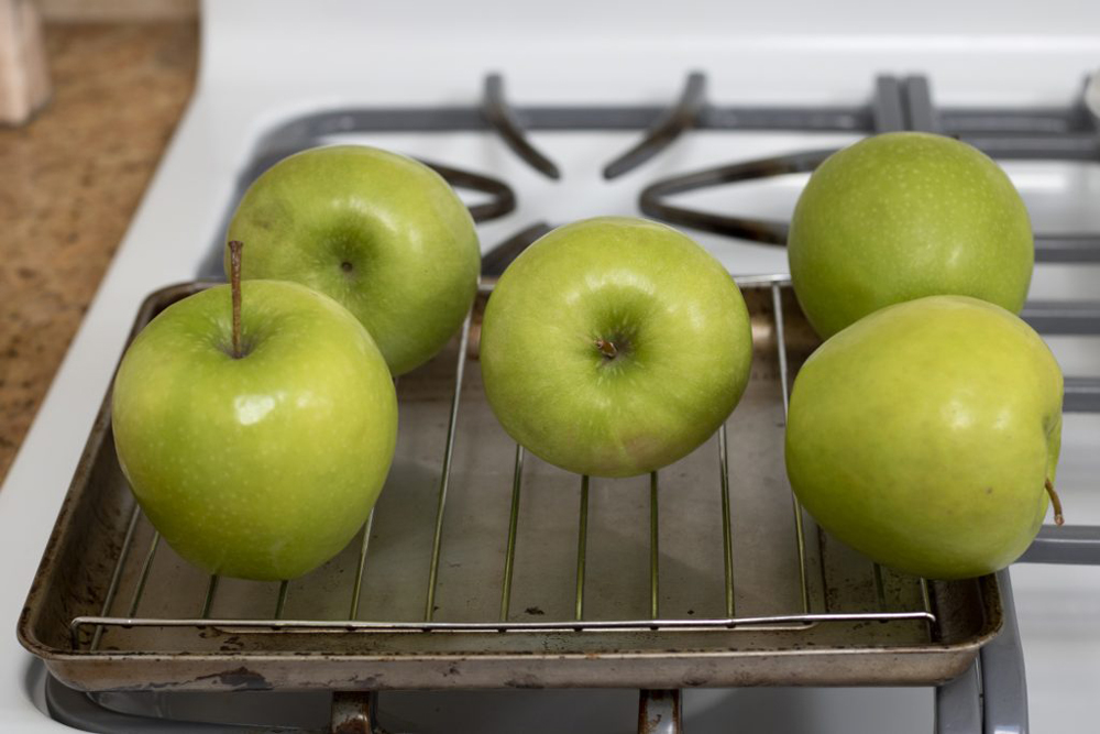 Some green granny smith apples sitting on a rack.