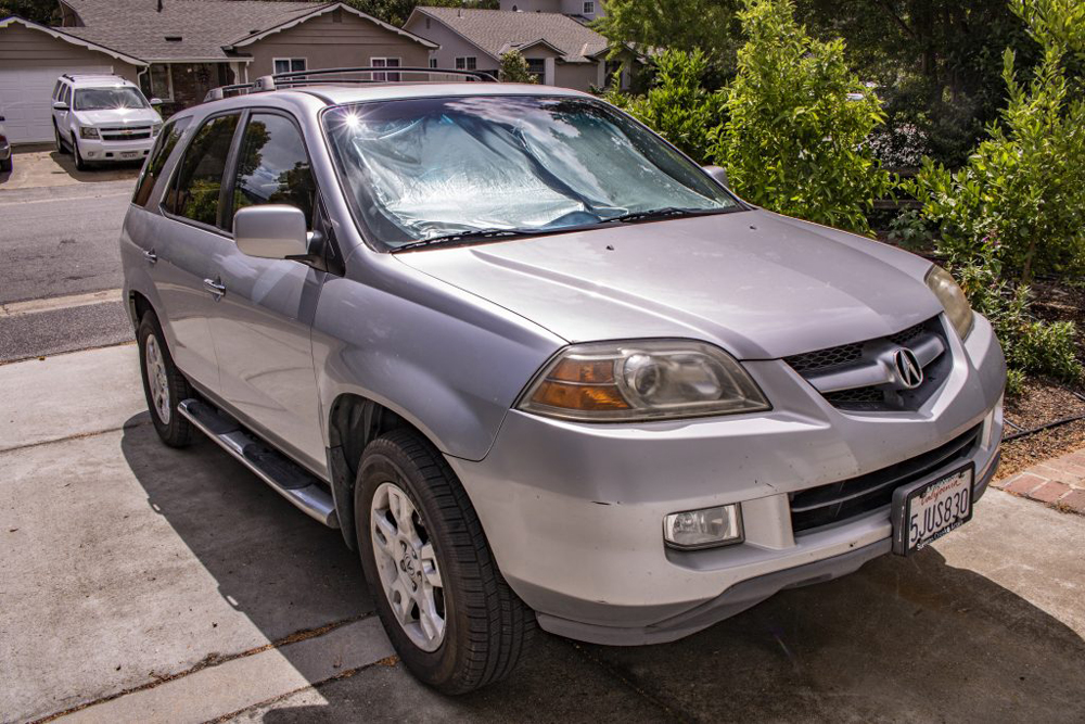 A photo of a car. To be specific, it is a silver SUV from the early 2000's—a 2002 Acura MDX, with the Sport Touring Package, I believe.
