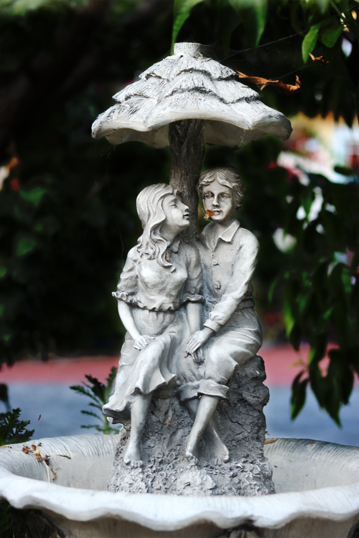 a statue of a young girl and boy on a dried fountain