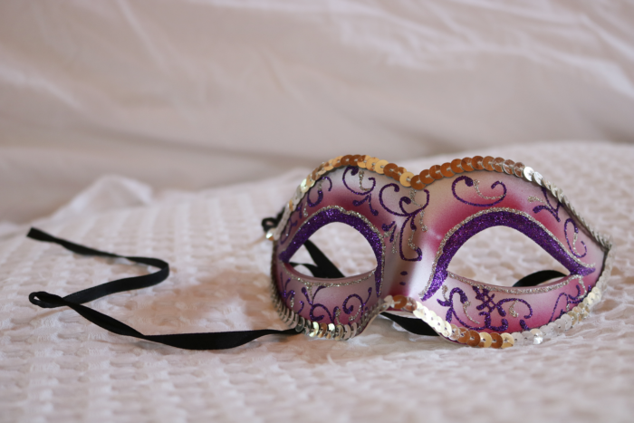 a colorful festival mask on top of a white pillow