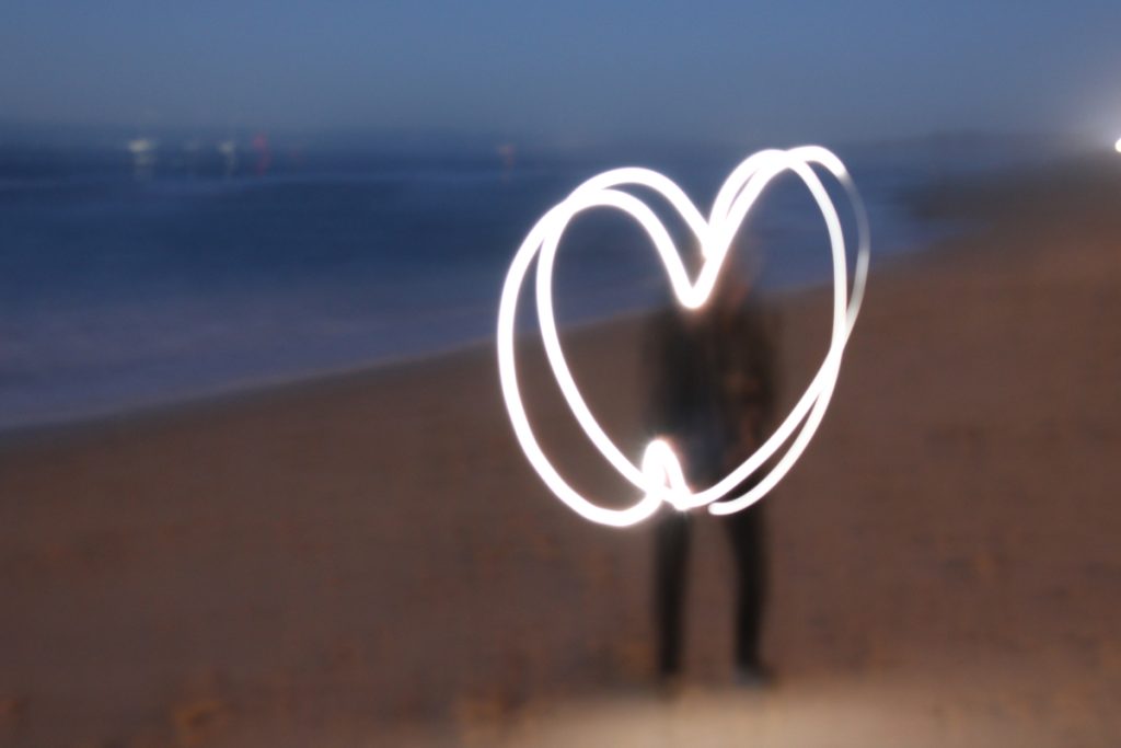 A blurry image of a beach with a shape resembling a heart drawn over it with light.