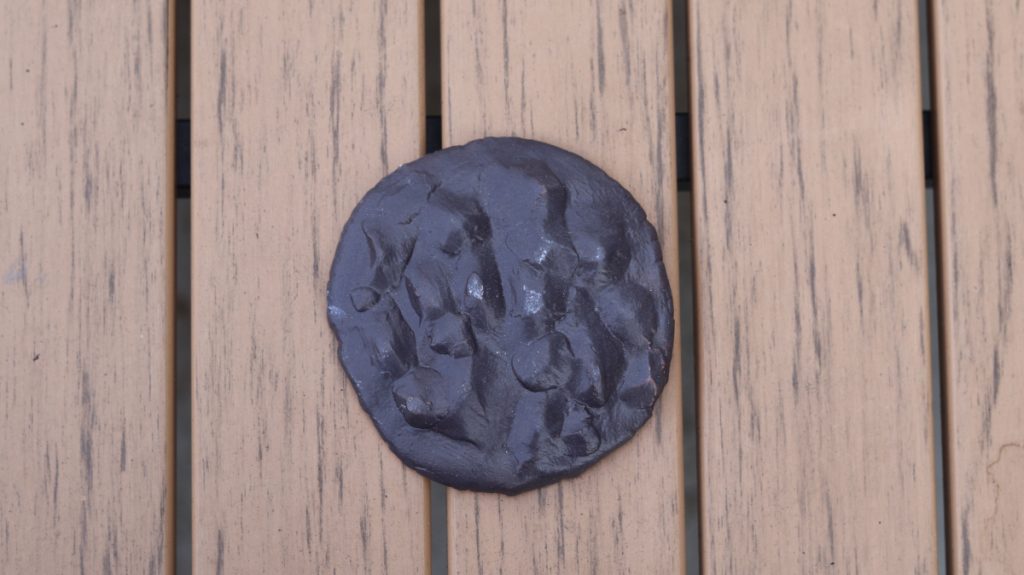 Clay black circle with bumps and crevasses 