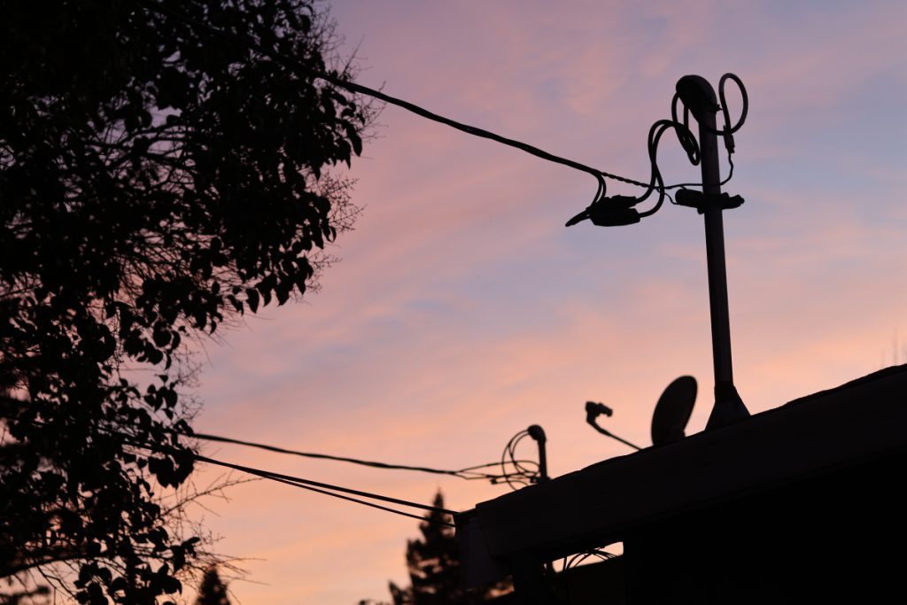 A beautiful dark sunset photo with the silhouette of a tree and wire post. 