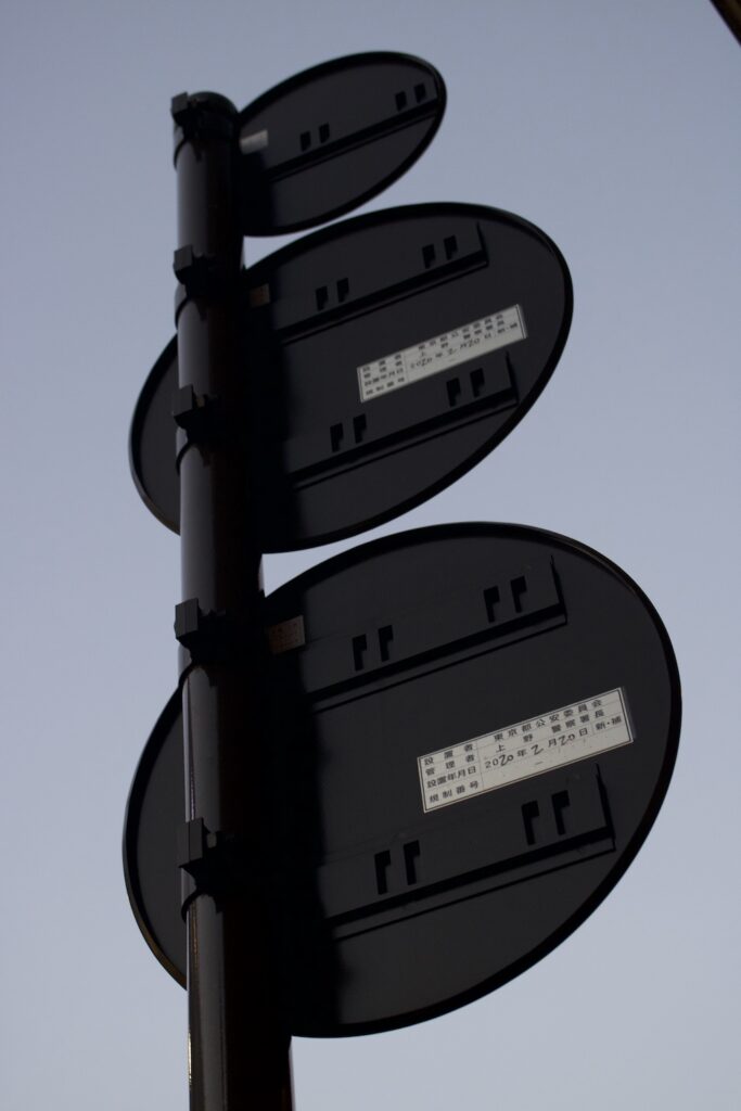 a photo of a pole with three circular signs on it from behind against the sky.