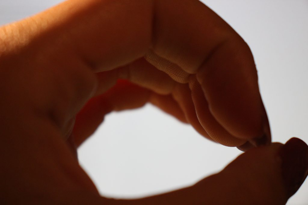 The photo shows a hand held in the form of an 'o' and is up close to the camera lens. The hand acts as a lens itself, and is focused in on the hand rather than what the hand is showing. 