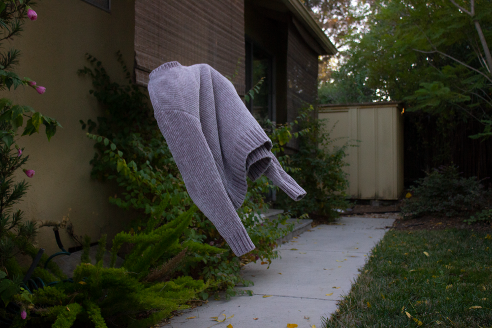 The image pictures a sweater floating in the midst of a pathway. 