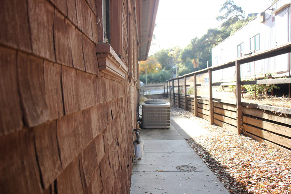 A building of reddish wood color and a wooden fence. 