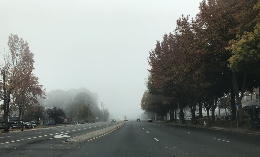 A picture of a wide road in the fog.
