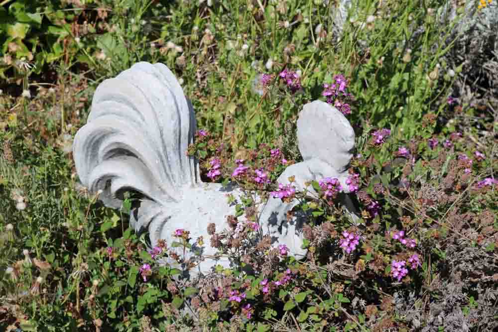 A photo of a chicken sculpture in a bush