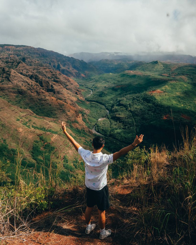 a man standing in front of a beautiful view of the mountains in hawaii,