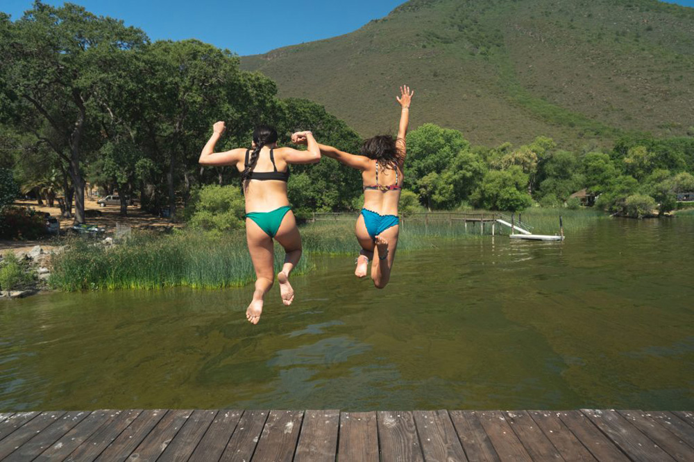 a photo of two teenage girls jumping off a dock into water.