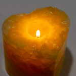 A yellow, heart-shape candle burning