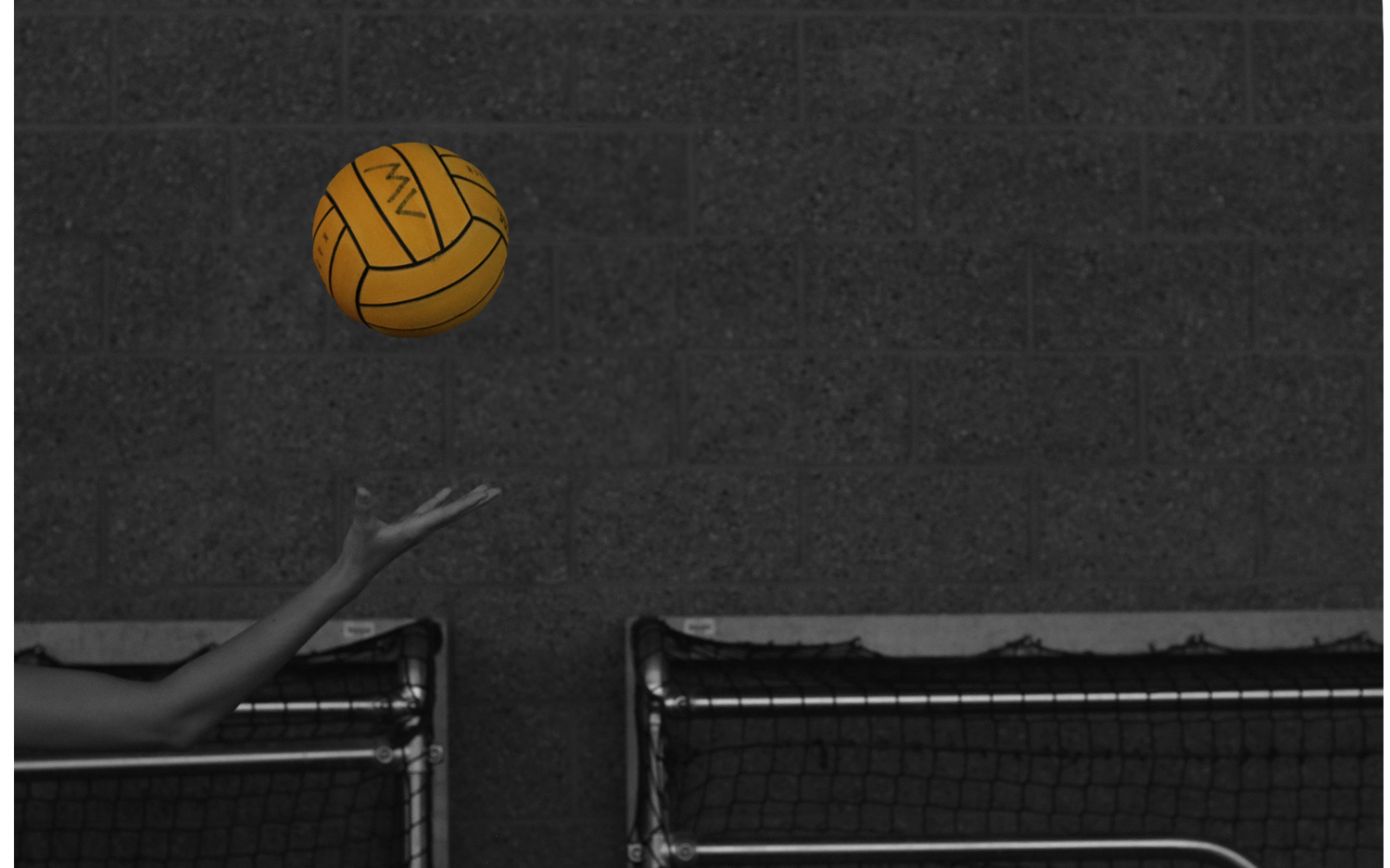 On the left side of the photo there is an arm and above the arm in the air there is a waterpolo ball. The entire image is in black and white except for the ball which is a vibrant yellow.