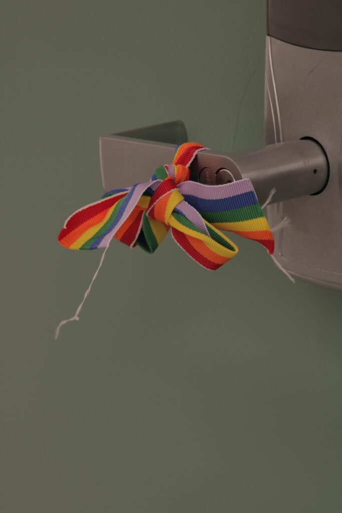 Rainbow (Pride) Ribbon tied on a door handle.