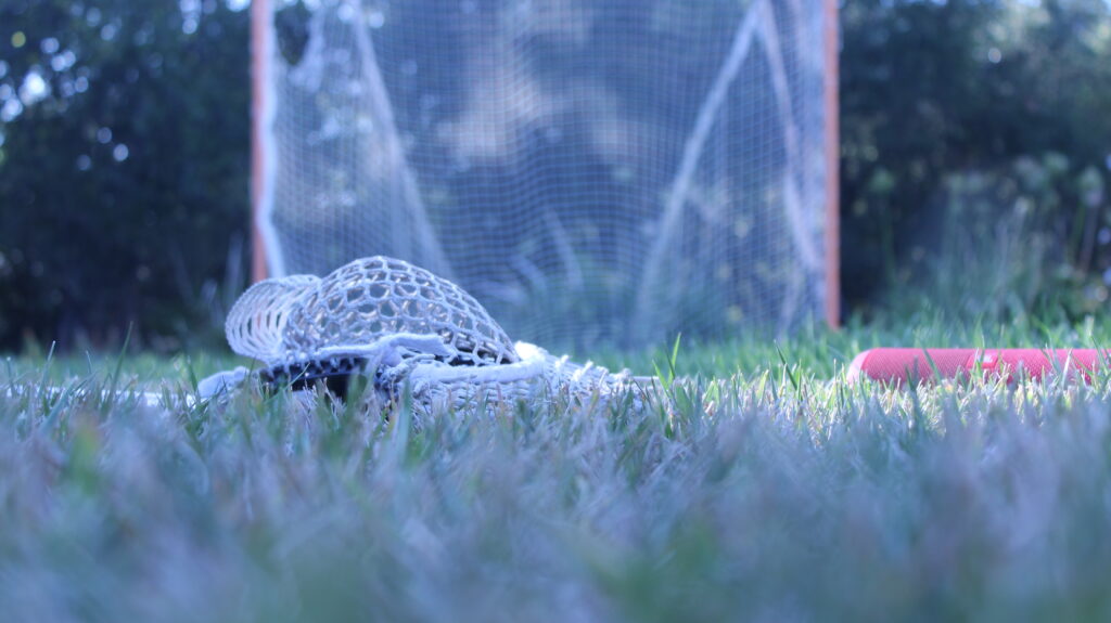 Lacrosse stick, speaker, and lacrosse goal sitting in my front yard on a nice afternoon