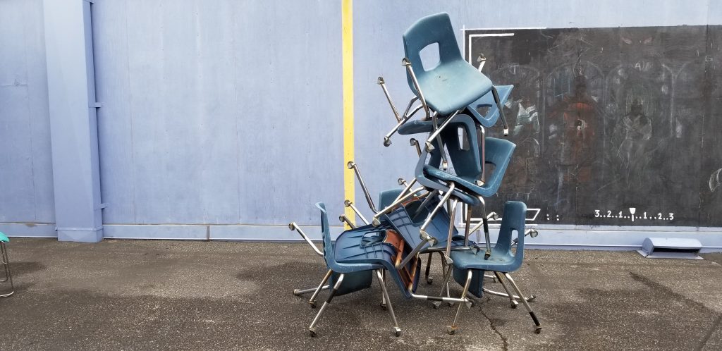 Some chairs very messily stacked atop one another