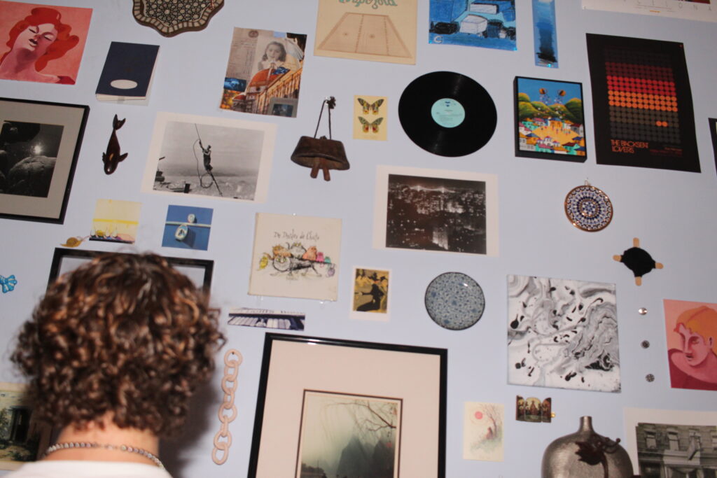 wall of pictures, objects, posters and mementoes with the back of my head in the foreground 