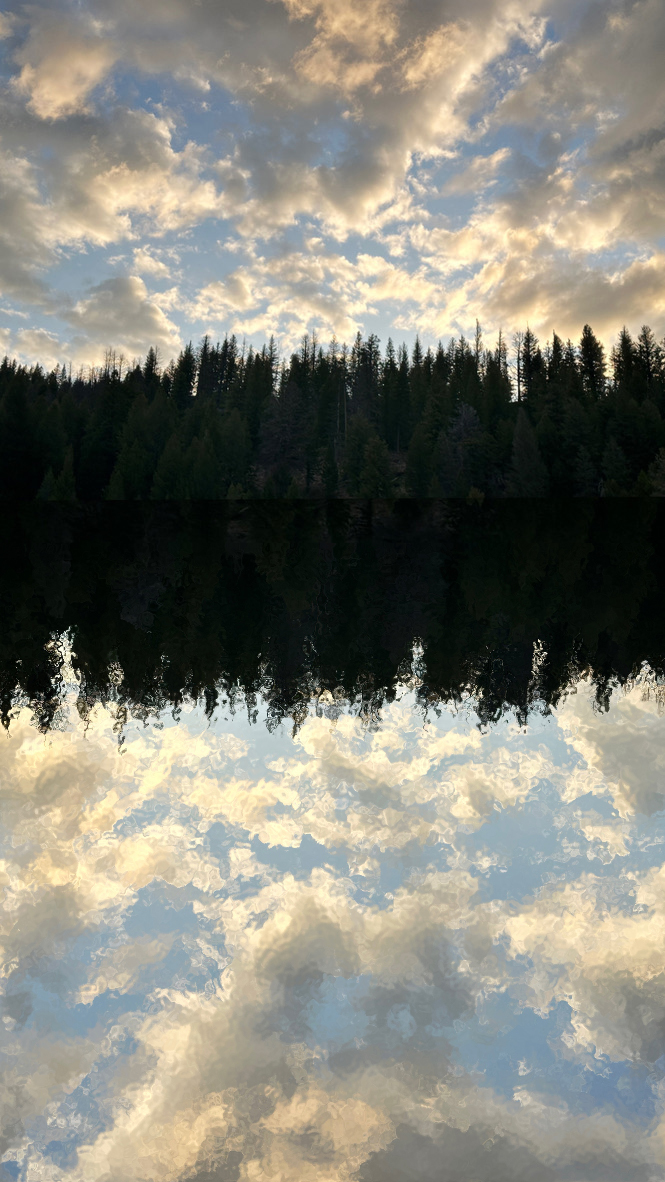 Reflection of shoreline onto lake with clouds